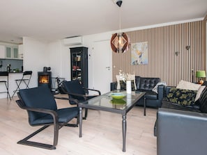 A modern living room with a glass coffee table, black leather sofa, and a fireplace. - 6 Person Holiday Home in Ebeltoft (Ebeltoft)