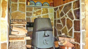 A stone fireplace with a wood stove, a copper pot, and a stack of firewood. - 7 Person Holiday Home in Oppstryn (Stryn)
