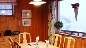 A wooden dining table with chairs, a window with a view, and a hanging flower basket. - 7 Person Holiday Home in Oppstryn (Stryn)