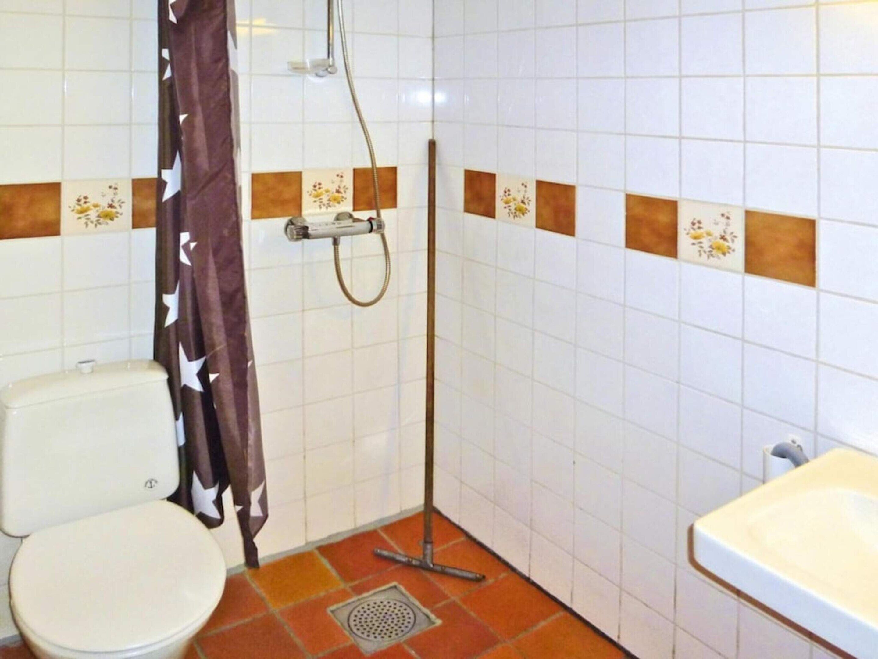 A bathroom with a toilet, shower, and sink.