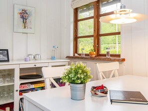 A well-lit room with a large window, a desk with a lamp, a potted plant, and a table with a notebook.
