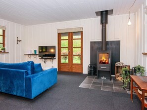 Una sala de estar acogedora con un sofá azul, un televisor, una chimenea y un ventanal grande.