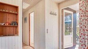 A hallway with wooden flooring, a wooden shelf with items, a door, and a window with a view of trees. - 4 Person Holiday Home in Aakirkeby (Akirkeby)