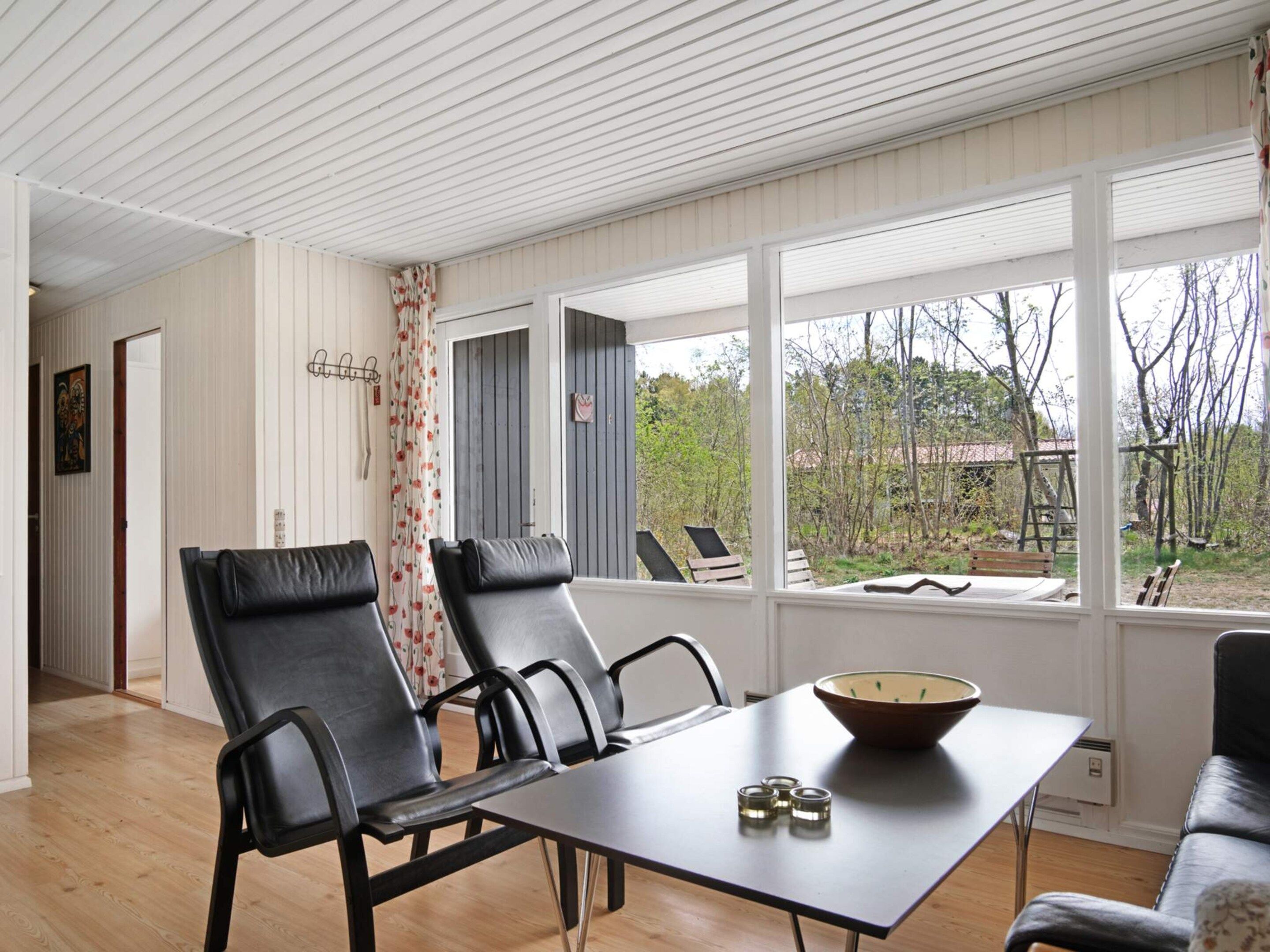 Una habitación con una mesa de comedor, cuatro sillas, un cuenco y vistas al exterior.