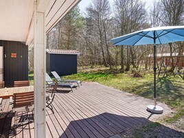 Una terraza de madera con mobiliario exterior y un paraguas azul.