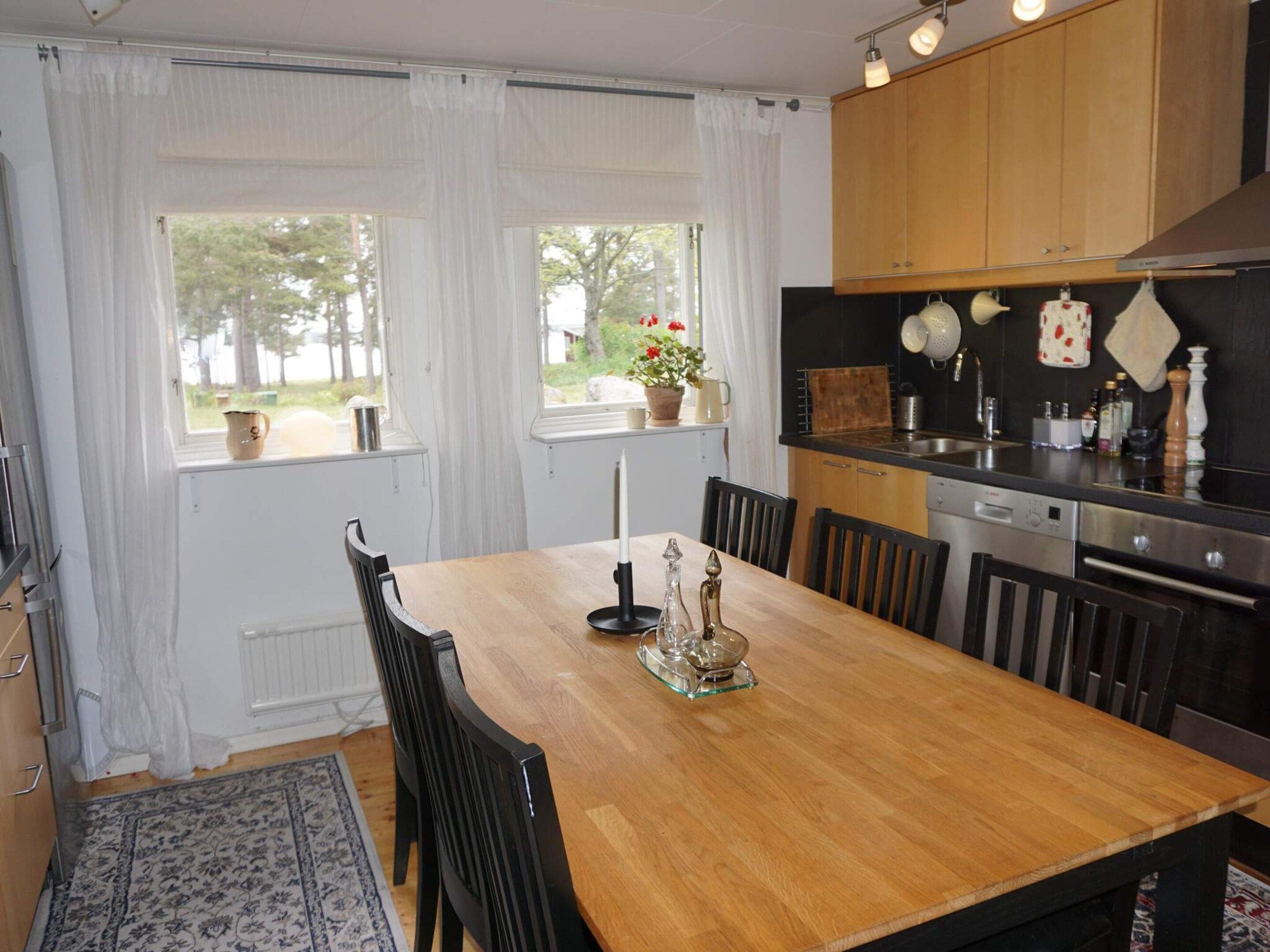 A modern kitchen with wooden cabinets, a black countertop, and a dining area with a wooden table and chairs.