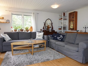 A cozy living room with a grey sofa, a wooden coffee table, and a large window with curtains. - 6 Person Holiday Home in Monsteras (Monsteras)