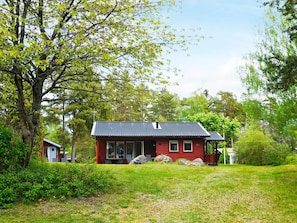 A red house with a dark roof, surrounded by a grassy area and trees. - 6 Person Holiday Home in Monsteras (Monsteras)