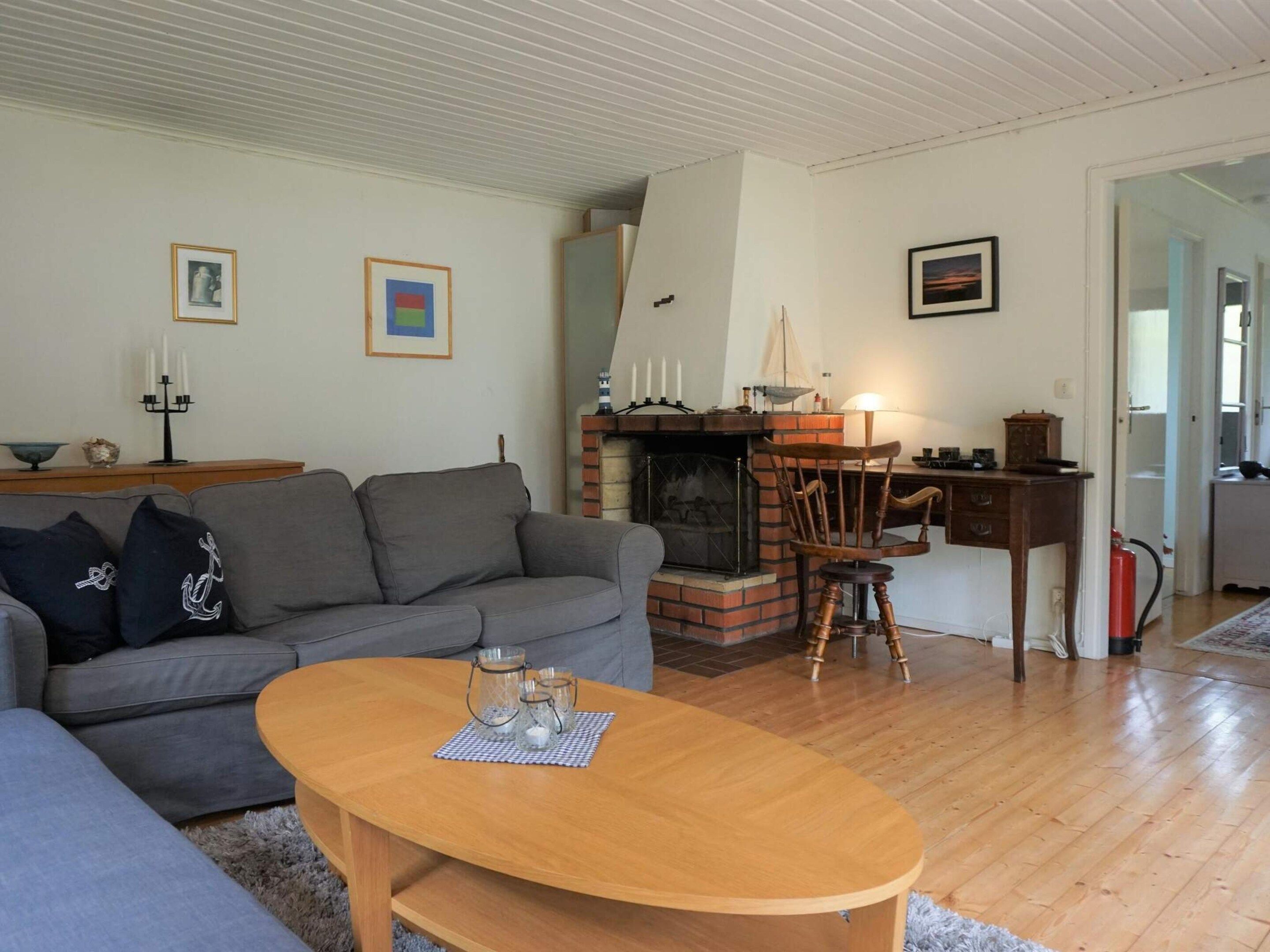 Un salon comprenant un canapé, une table basse en bois, une cheminée et un coin repas avec une chaise et une table.