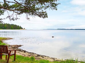 A lakeside view with a wooden bench and a calm water body. - 6 Person Holiday Home in Monsteras (Monsteras)