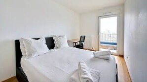 Une chambre d’hôtel avec un lit, un bureau et une vue sur la ville, grâce à une grande fenêtre.