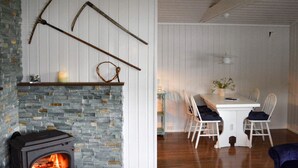 A cozy living room with a stone fireplace, wooden dining table, and chairs. - 4 Person Holiday Home in Utvik-by Traum (Stryn)