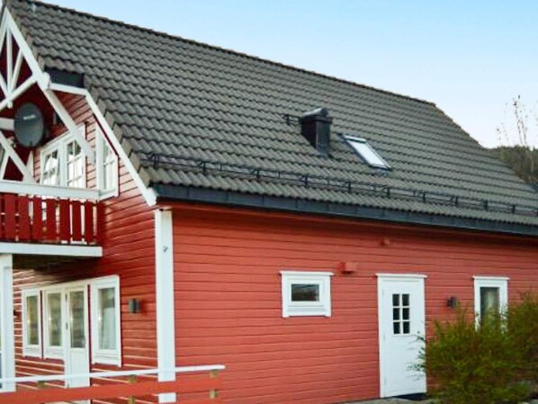 A red wooden house with a white porch and a grey tiled roof. - 4 Person Holiday Home in Maloy-by Traum (Kinn)