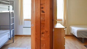 A room with bunk beds, a wooden wardrobe, and a window. - 4 Person Holiday Home in Maloy-by Traum (Kinn)