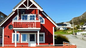 A red two-story house with a balcony, a satellite dish, and a small porch. - 4 Person Holiday Home in Maloy-by Traum (Kinn)