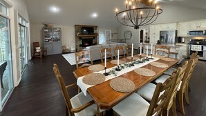 A spacious dining area with a long wooden table, surrounded by chairs, and a chandelier overhead. - Lake Front House with Dock, Kayaks, and Boat Slip (Troy)