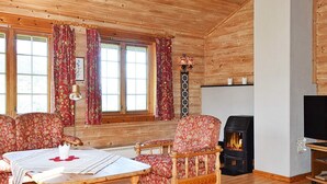 Un intérieur chaleureux de chalet en bois, avec une cheminée, des meubles en bois et de grandes fenêtres.
