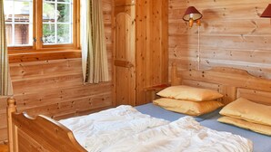 Une pièce de type cabane en bois, comprenant un lit, une fenêtre, des rideaux et une lampe fixée au mur.