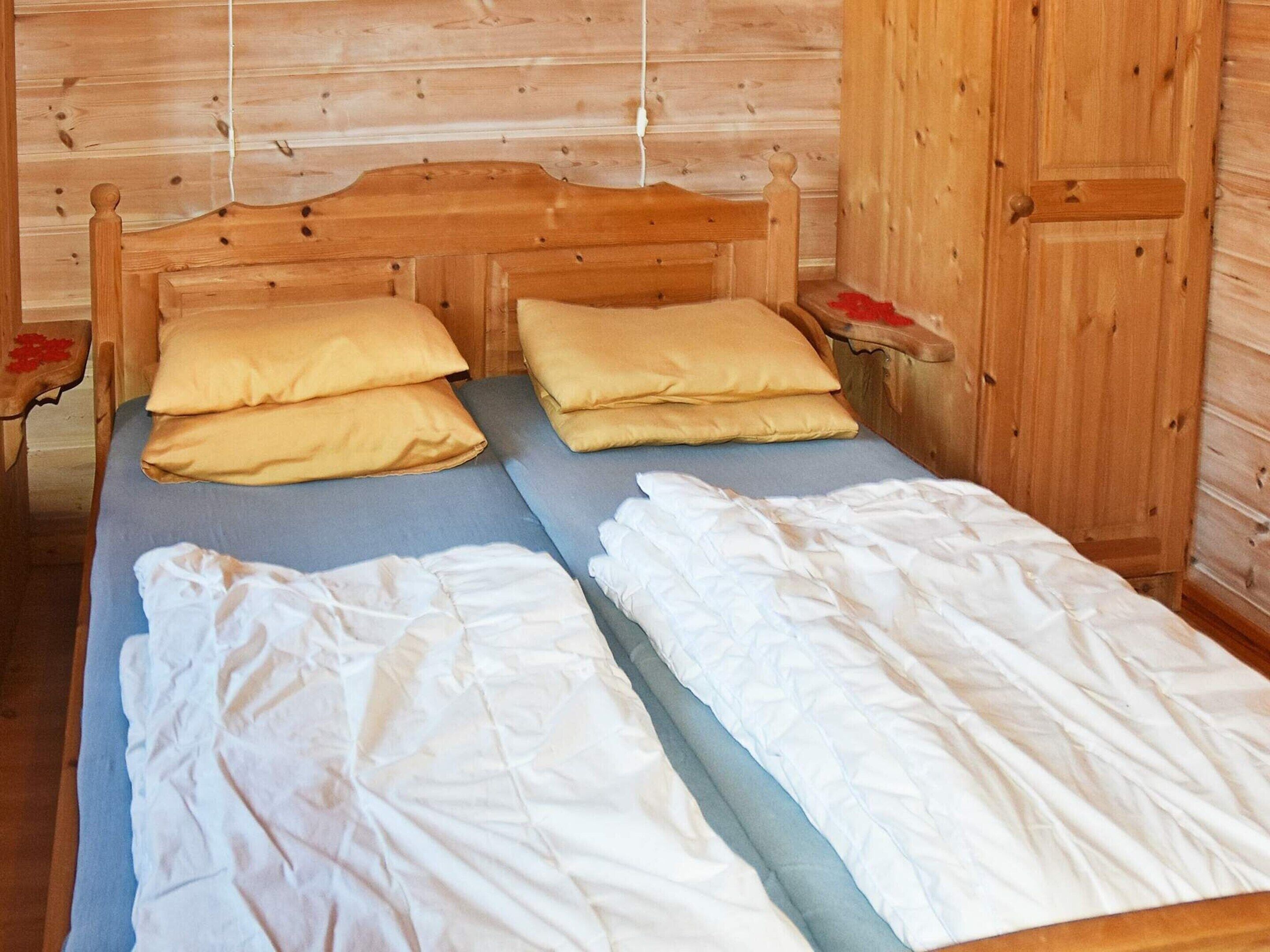 A wooden cabin-style room with a bed, pillows, and a wardrobe.
