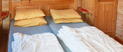 A wooden cabin-style room with a bed, pillows, and a wardrobe.