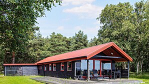 A cabin with a red roof, large windows, and a deck area. - 4 Person Holiday Home in Laeso (Læsø)