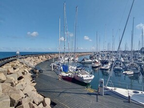 A marina with multiple boats docked along a wooden pier.