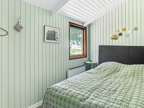 A room with a bed, a window, a framed picture, and a wall with circular decorations.