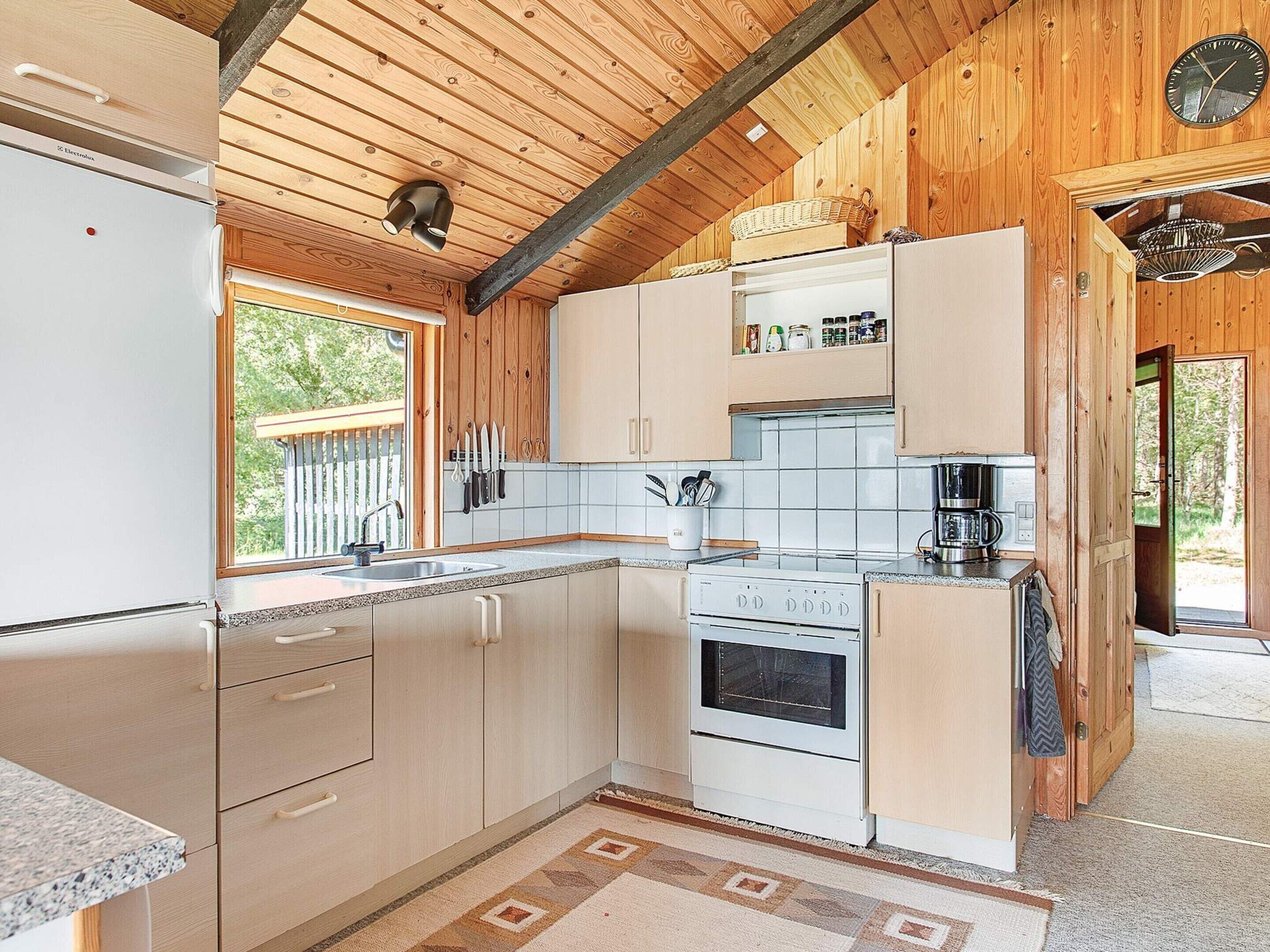 A kitchen with wooden cabinets, a refrigerator, a stove, and a coffee maker.