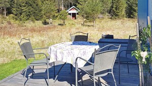 A wooden deck with a table and chairs, a small shed in the background, and a potted plant on the right. - 4 Person Holiday Home in Ed (Ed)