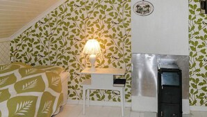 A bedroom with a bed, a nightstand, a lamp, a heater, and a patterned wallpaper. - 4 Person Holiday Home in Ed (Ed)