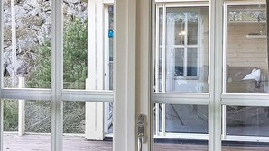 Eine Holzterrasse mit einer Glastür, die zu einem Raum führt.