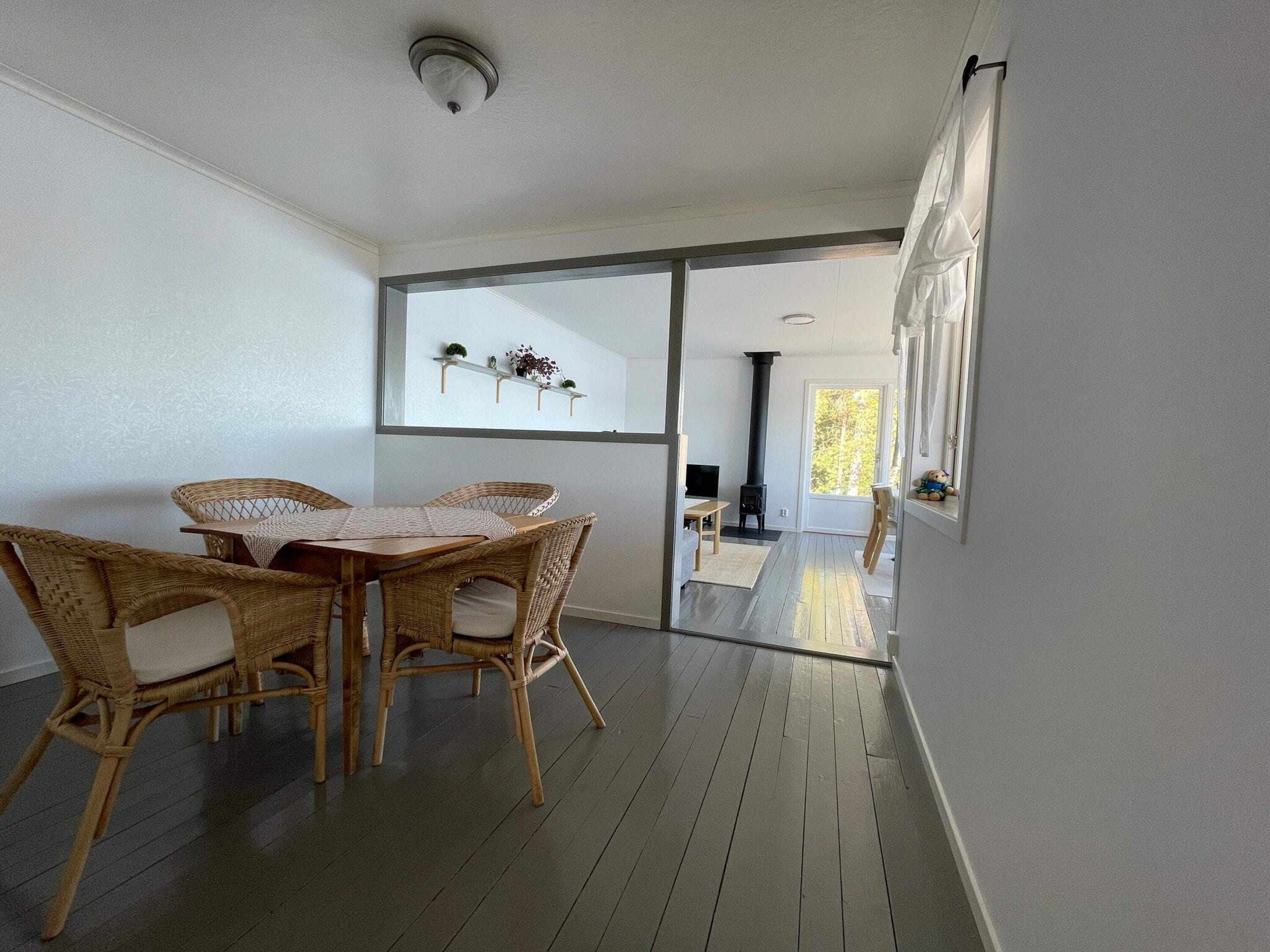 A room with a dining table and chairs, a fireplace, and a view through a glass door.