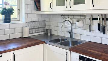 Cuina amb armaris blancs, un rentaplatos de Bosch i un vàter d'acer inoxidable.