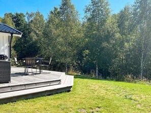 A deck with outdoor furniture, a barbecue grill, and a view of a forested area. - 4 Person Holiday Home in Hacksvik (Håcksvik)