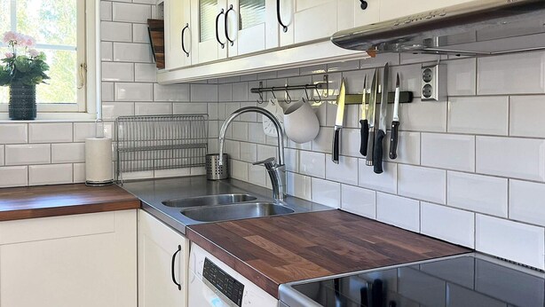 A kitchen with white cabinets, a stainless steel sink, a wooden countertop, and a built-in oven. - 4 Person Holiday Home in Hacksvik (Håcksvik)