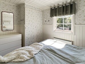 A bedroom with a bed, a dresser, a window with curtains, a mirror, and a wardrobe. - 4 Person Holiday Home in Hacksvik-by Traum (Håcksvik)