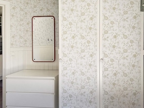 A bathroom with a white vanity, a mirror with a wooden frame, and floral wallpaper. - 4 Person Holiday Home in Hacksvik (Håcksvik)