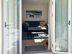 A room with a sofa, a coffee table, and a painting on the wall. - 4 Person Holiday Home in Hacksvik (Håcksvik)