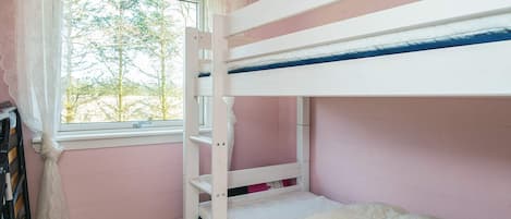 A bunk bed room with a window, wooden floor, and pink walls.