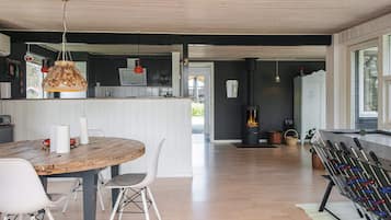 Una cocina moderna con una mesa de madera, sillas blancas y una estufa.