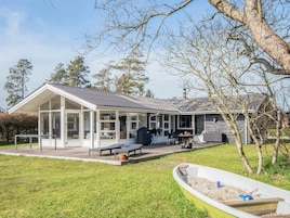 Una casa con un porche cubierto, mobiliario exterior y una piscina.