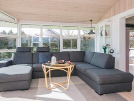 Una sala de estar moderna con un sofá modular, una mesita redonda y ventanas amplias con vistas al exterior.