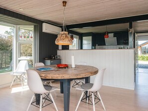 A dining area with a round wooden table, white chairs, and pendant lighting. - 5 Person Holiday Home in Tarm (Tarm)