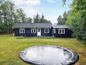 Ein zweistöckiges Haus mit einer Veranda und einem Trampolin im Garten.