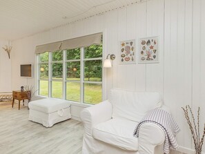 Ein Zimmer mit einem weißen Sofa, einem kleinen Tisch und einem großen Fenster.