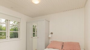A bedroom with a bed, a wardrobe, a window, and a wall-mounted lamp. - 4 Person Holiday Home in Hals (Hals)