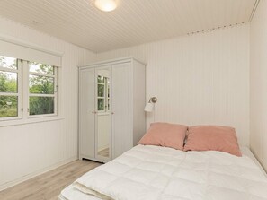 Ein Schlafzimmer mit Bett, Kleiderschrank, Fenster und einer Wandlampe.