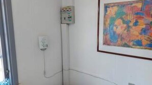Un baño con ducha, un enchufe y un cuadro abstracto en la pared.