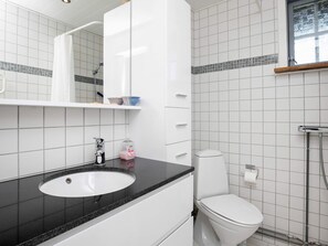 A modern bathroom with a white sink, black countertop, and a toilet. There is a mirror above the sink and a window above the toilet. - 4 Person Holiday Home in Hjorring (Hjørring)