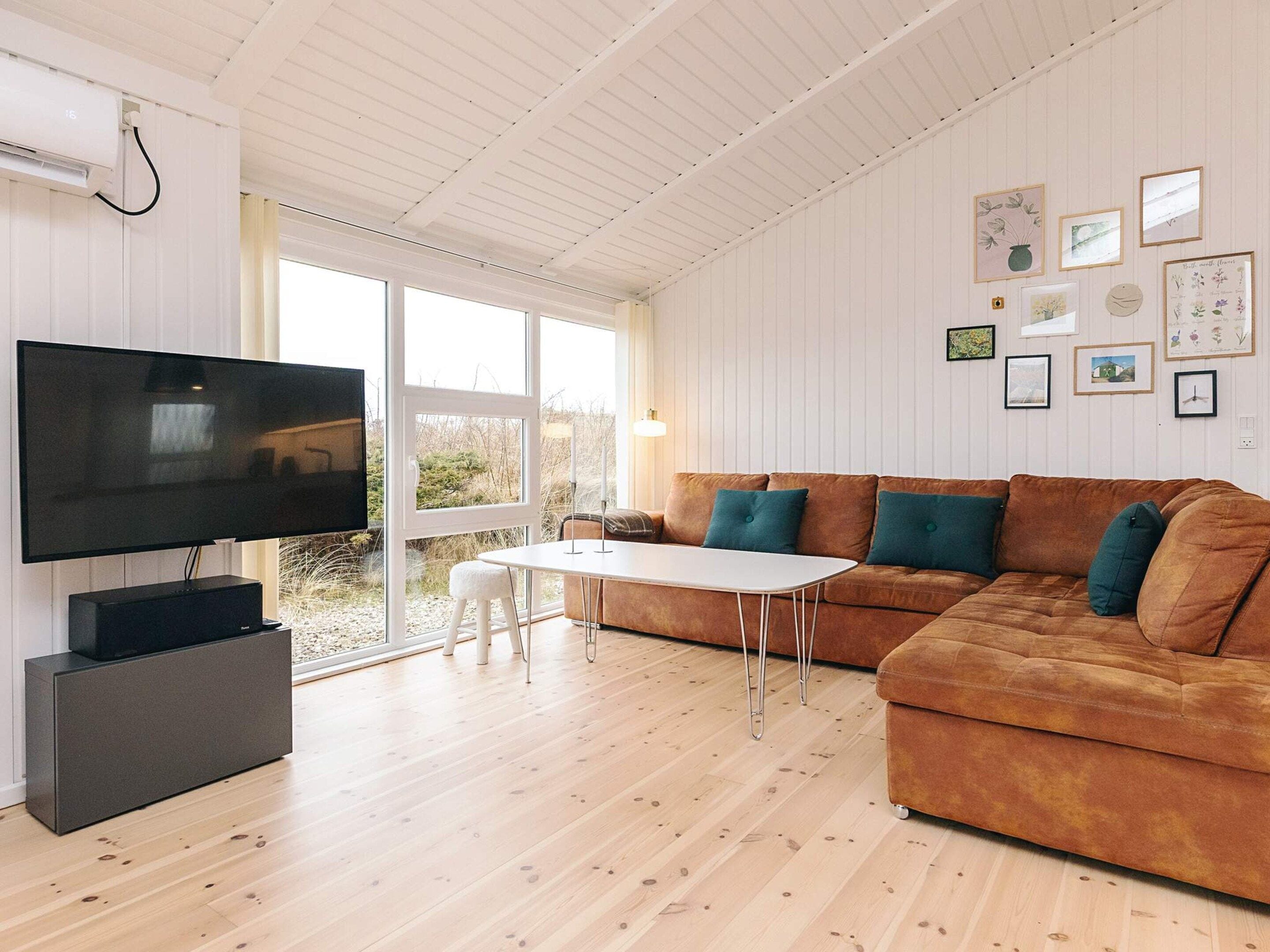 A modern living room with a flat-screen TV, a sofa, a coffee table, and a dining table.